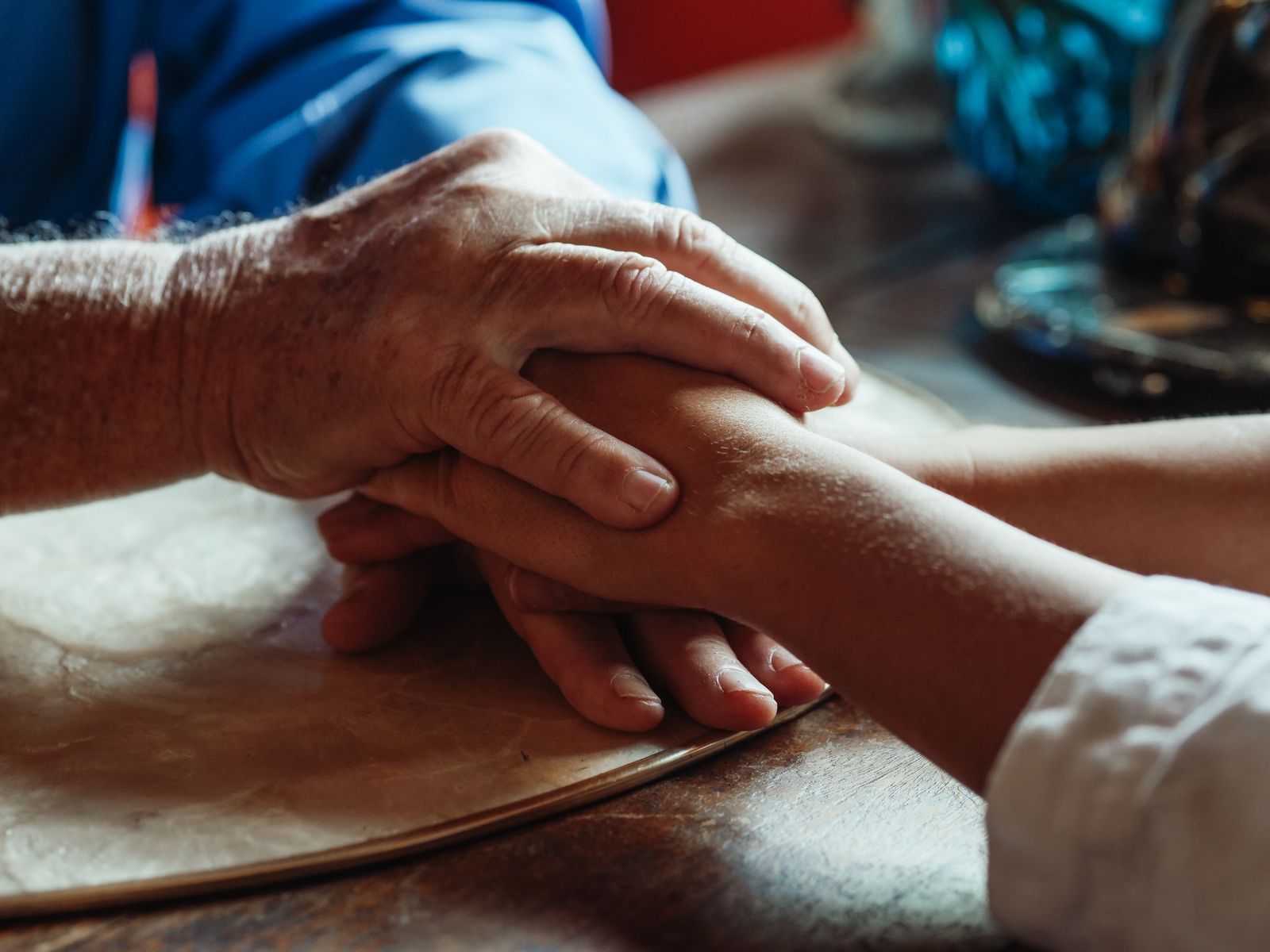 Close-up of an older person's hand resting on a younger person's hand