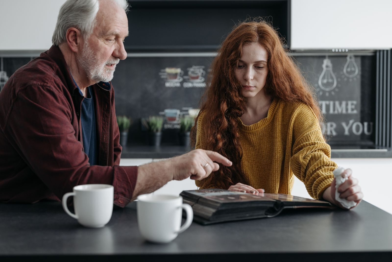 An older man and a younger woman looking through a photo album at a table